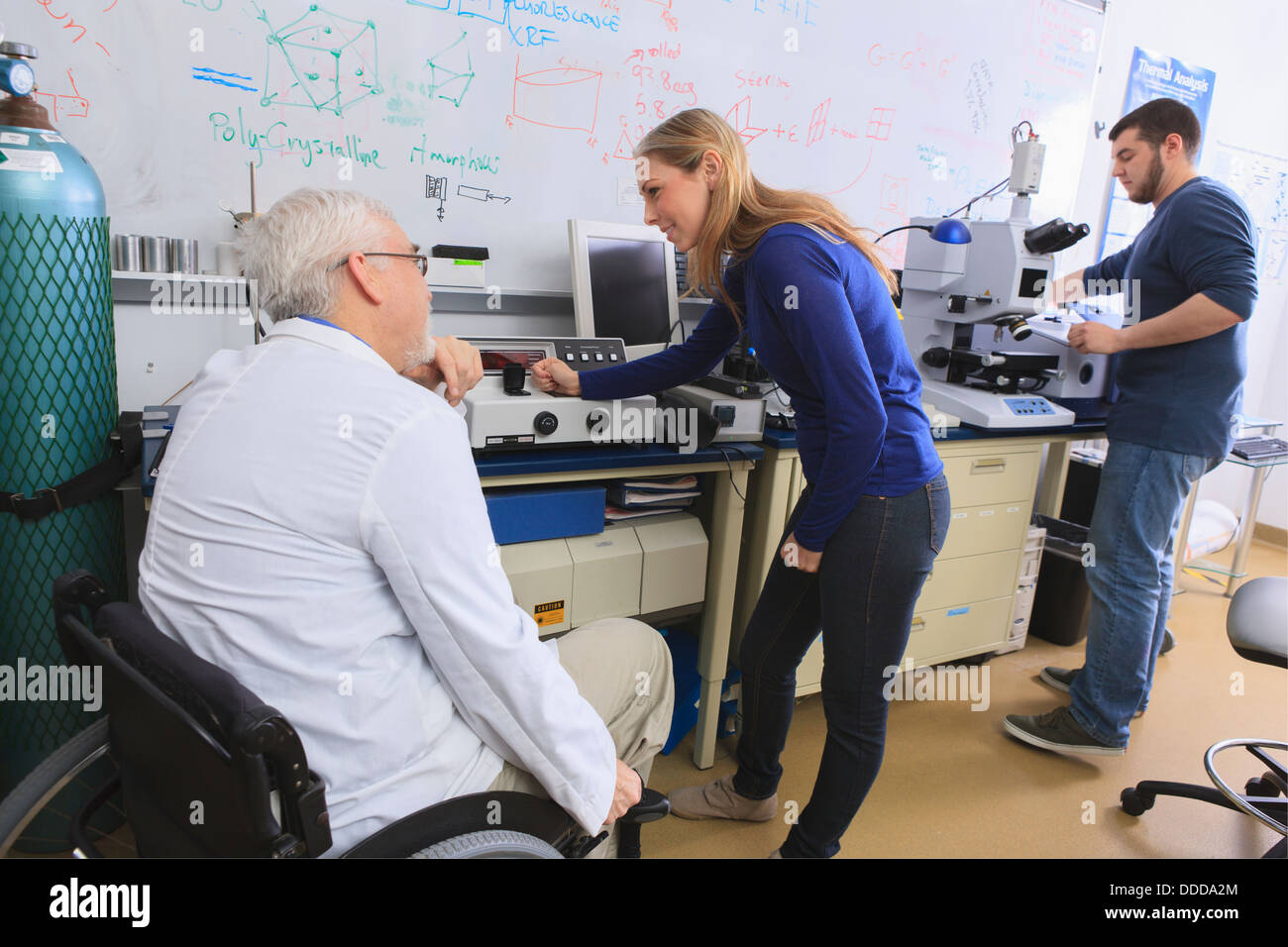 Il Professor con la distrofia muscolare di consigliare agli studenti di ingegneria in laboratorio di chimica lavora su x-ray analizzatori di fluorescenza Foto Stock
