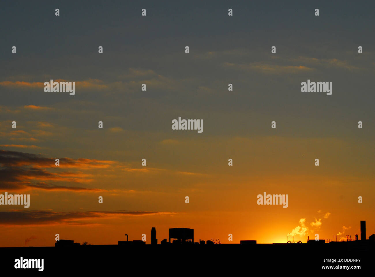 Tetto industriale stagliano arancione e viola le nuvole e cielo scuro al tramonto. Foto Stock