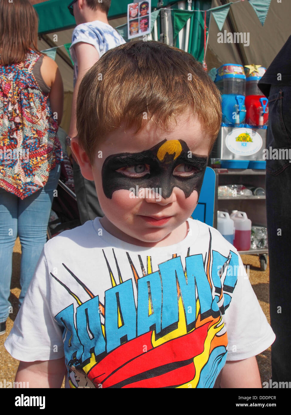 Ragazzo con la faccia del supereroe di vernice ad un festival estivo Foto Stock
