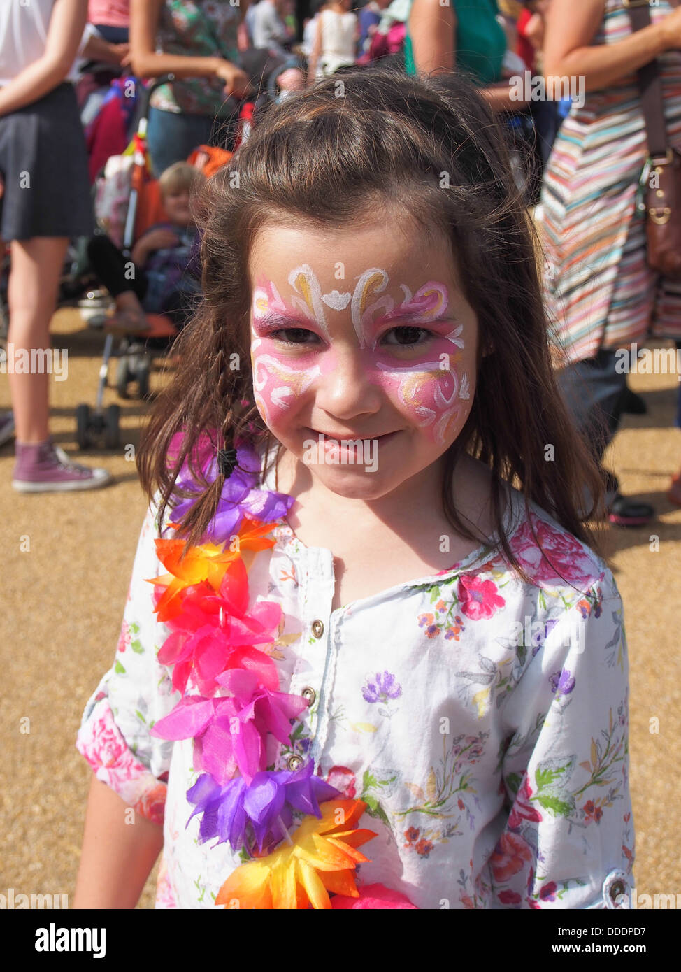 Ragazza giovane con il suo volto dipinto e indossa una ghirlanda di fiori in un festival estivo Foto Stock