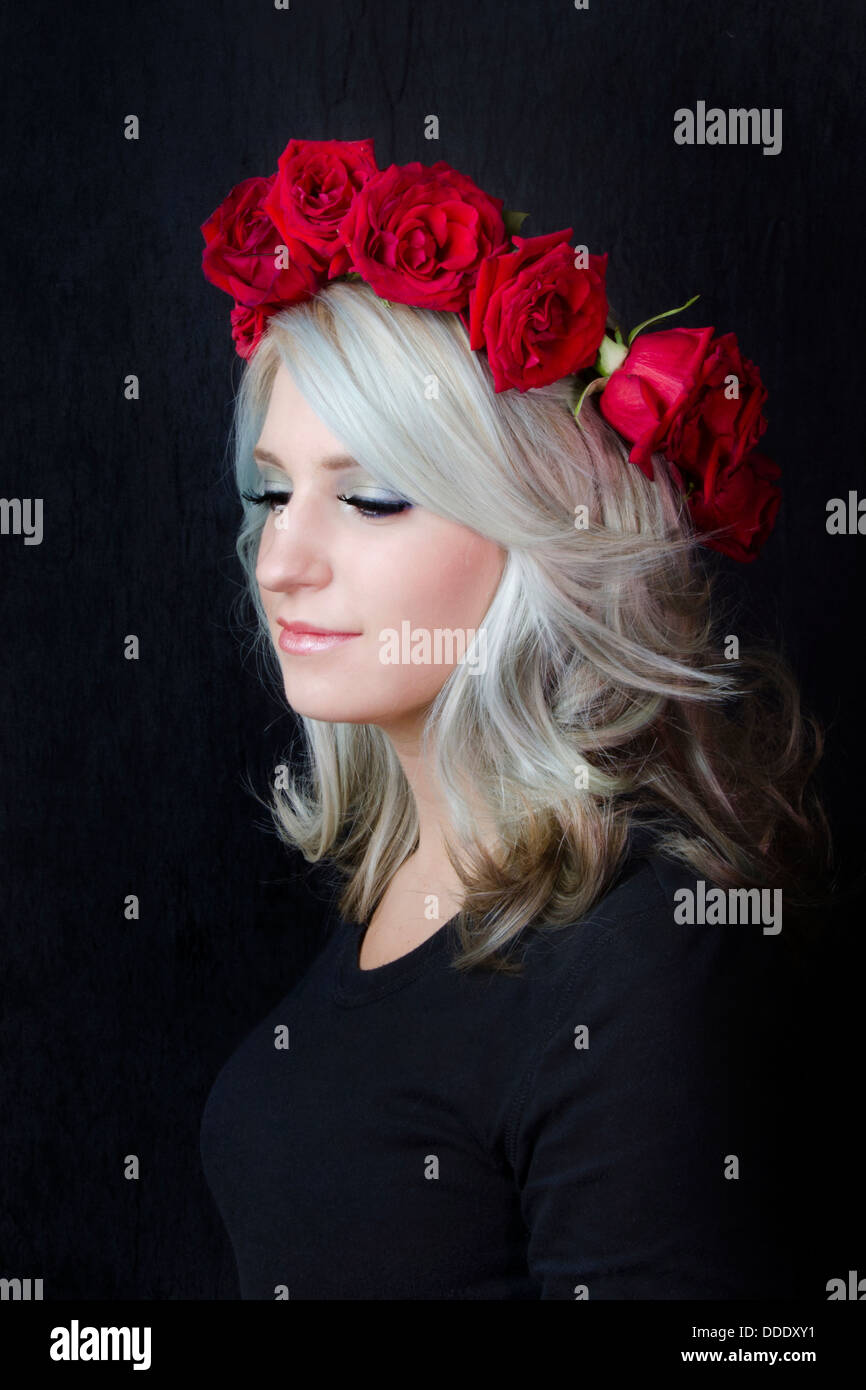 Una fotografia di bellezza della giovane donna/Model Adornata con rose rosse Foto Stock
