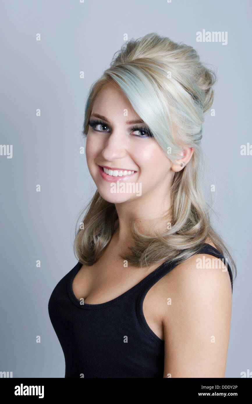 Un giovane bellezza modello con blu cooltone biondi capelli in mezzo fino a che fare in una impostazione di studio Foto Stock