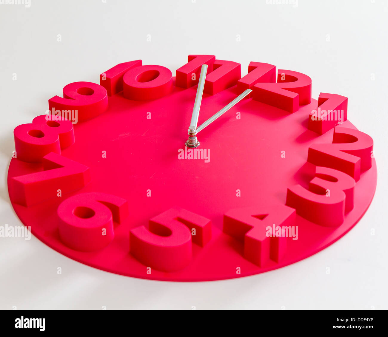 Orologio rosso su bianco isolato mostrante cinque minuti a mezzanotte Foto Stock