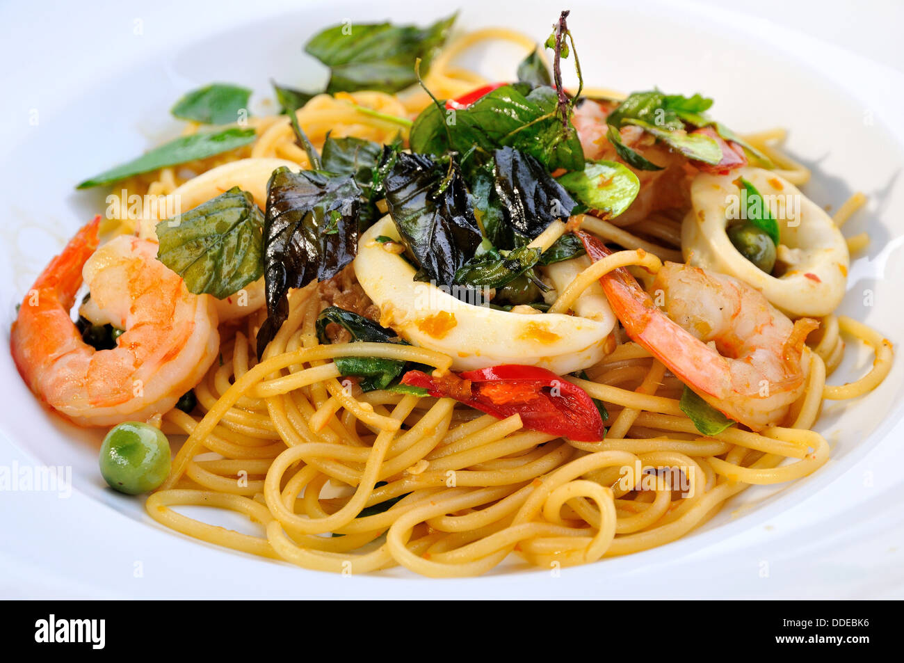 Stir-fried spicy spaghetti con gamberi, calamari e erbe tailandese Foto Stock