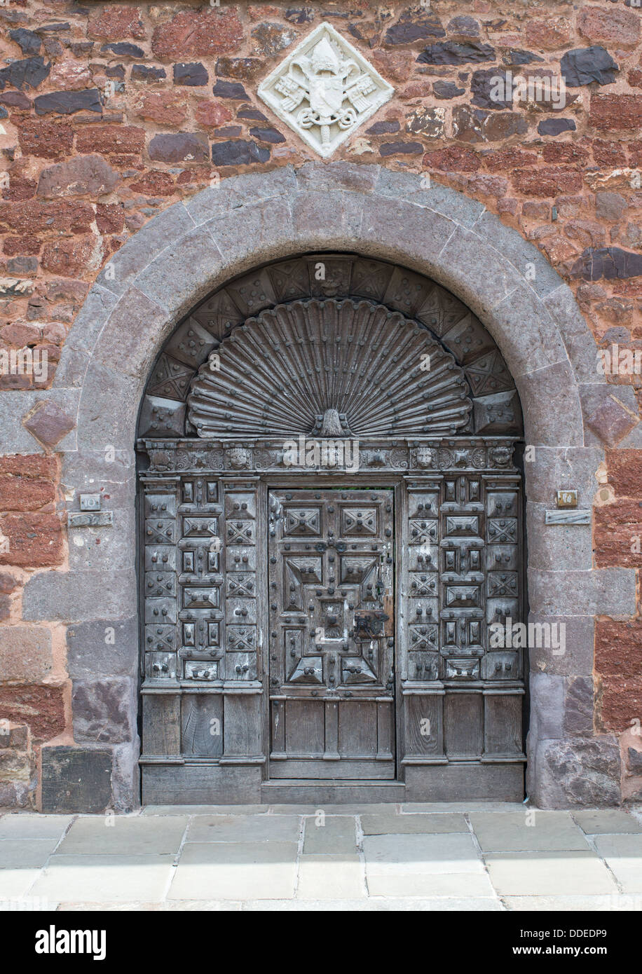 Le intricate sculture antiche in legno chiodati porta, e stemma, al cortile di 10 Cattedrale vicino a Exeter, England Regno Unito Foto Stock