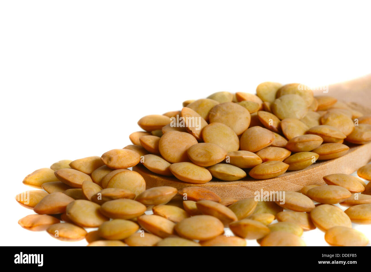 Macro shot di lenticchie su un cucchiaio di legno su sfondo bianco Foto Stock
