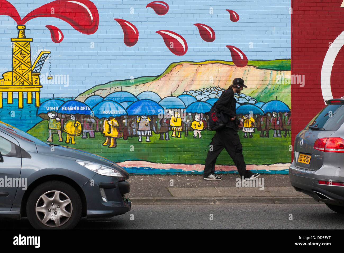 Murali politico dipinta su un muro a Belfast, nell'Irlanda del Nord mostra color sangue olio spray su un passante da sorridendo come lui a piedi. Foto Stock