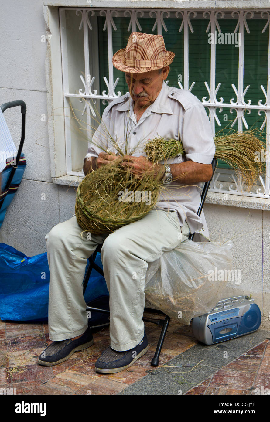Uomo spagnolo tessitura di un paniere di erba spagnolo nelle strade di Nerja, Andalusia, Spagna. Foto Stock