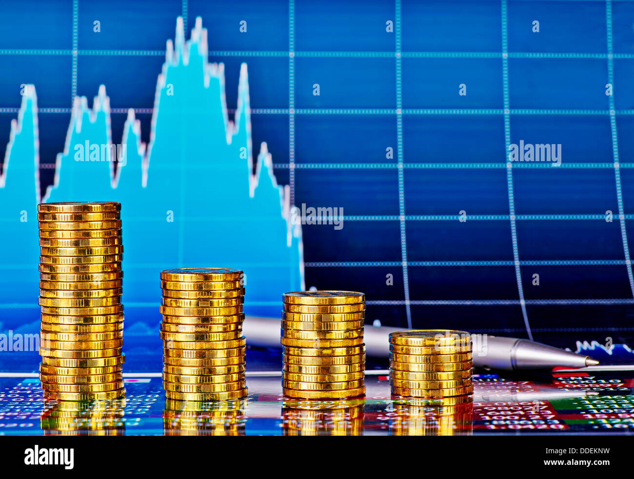 Tendenza ribassista grafico finanziario, penna e pile di monete d'oro. Messa a fuoco selettiva Foto Stock