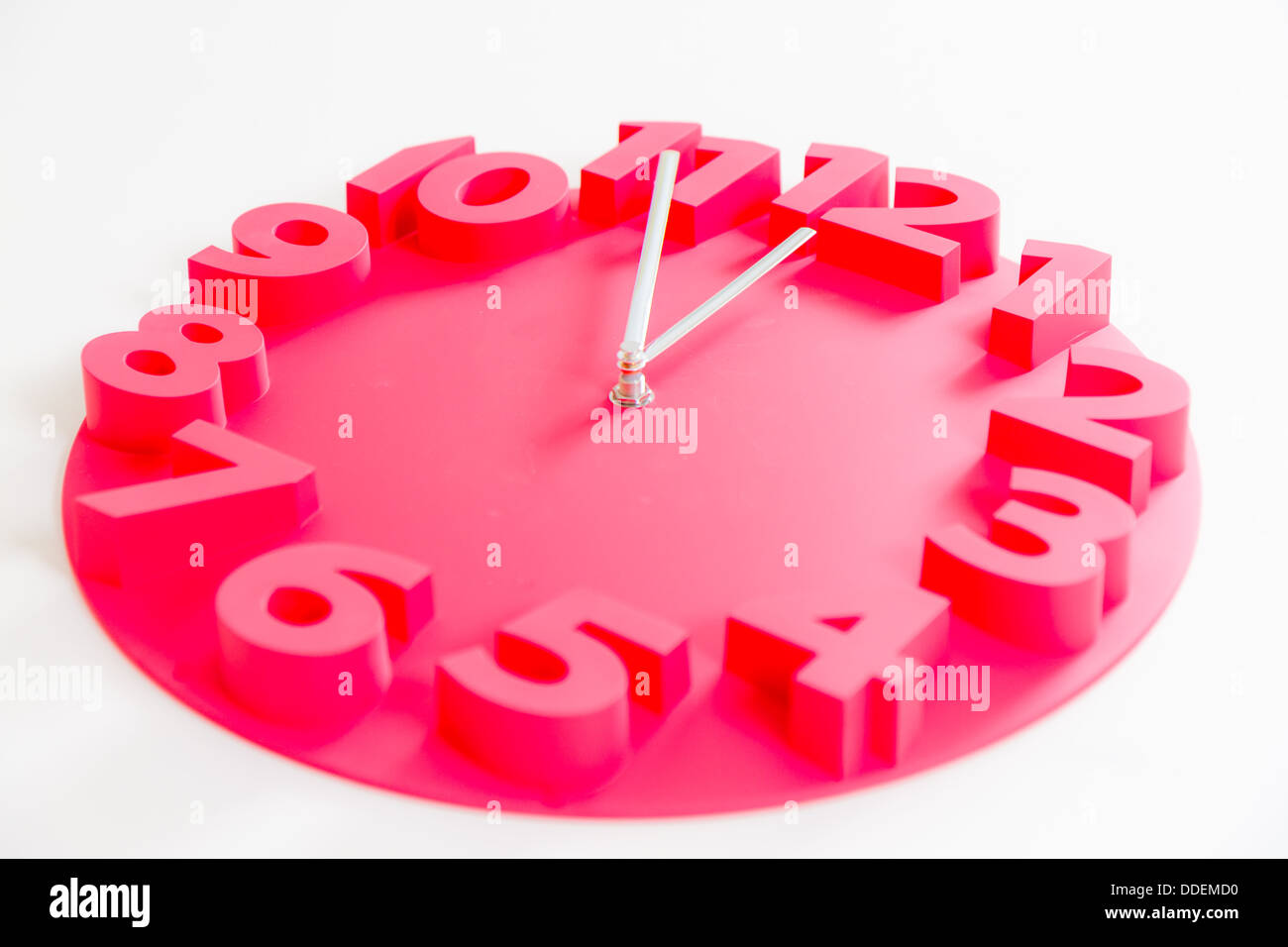 Orologio rosso su bianco isolato mostrante cinque minuti a mezzanotte Foto Stock