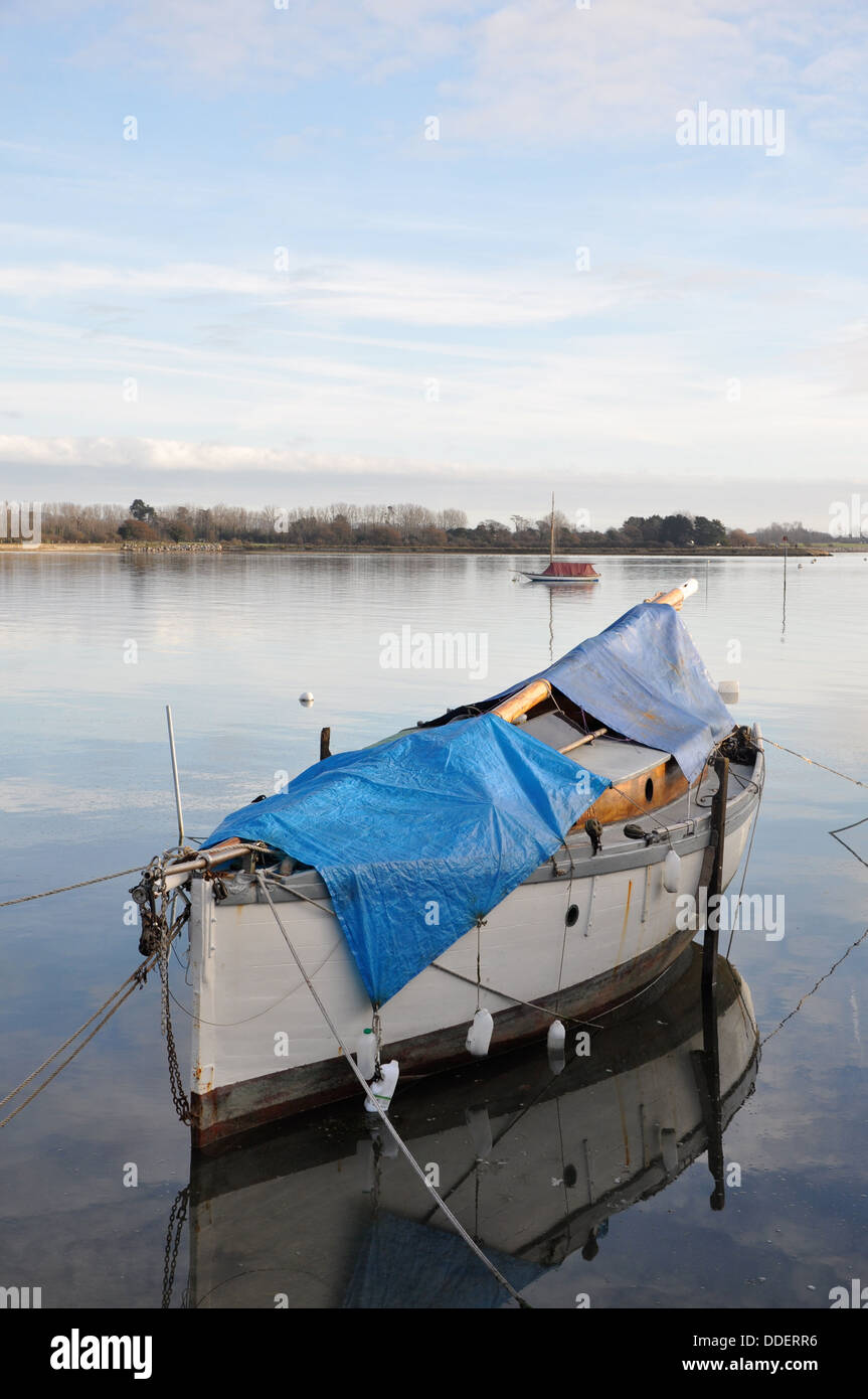 Vecchia barca a vela con coperchio in acque ancora vicino a Chichester Foto Stock