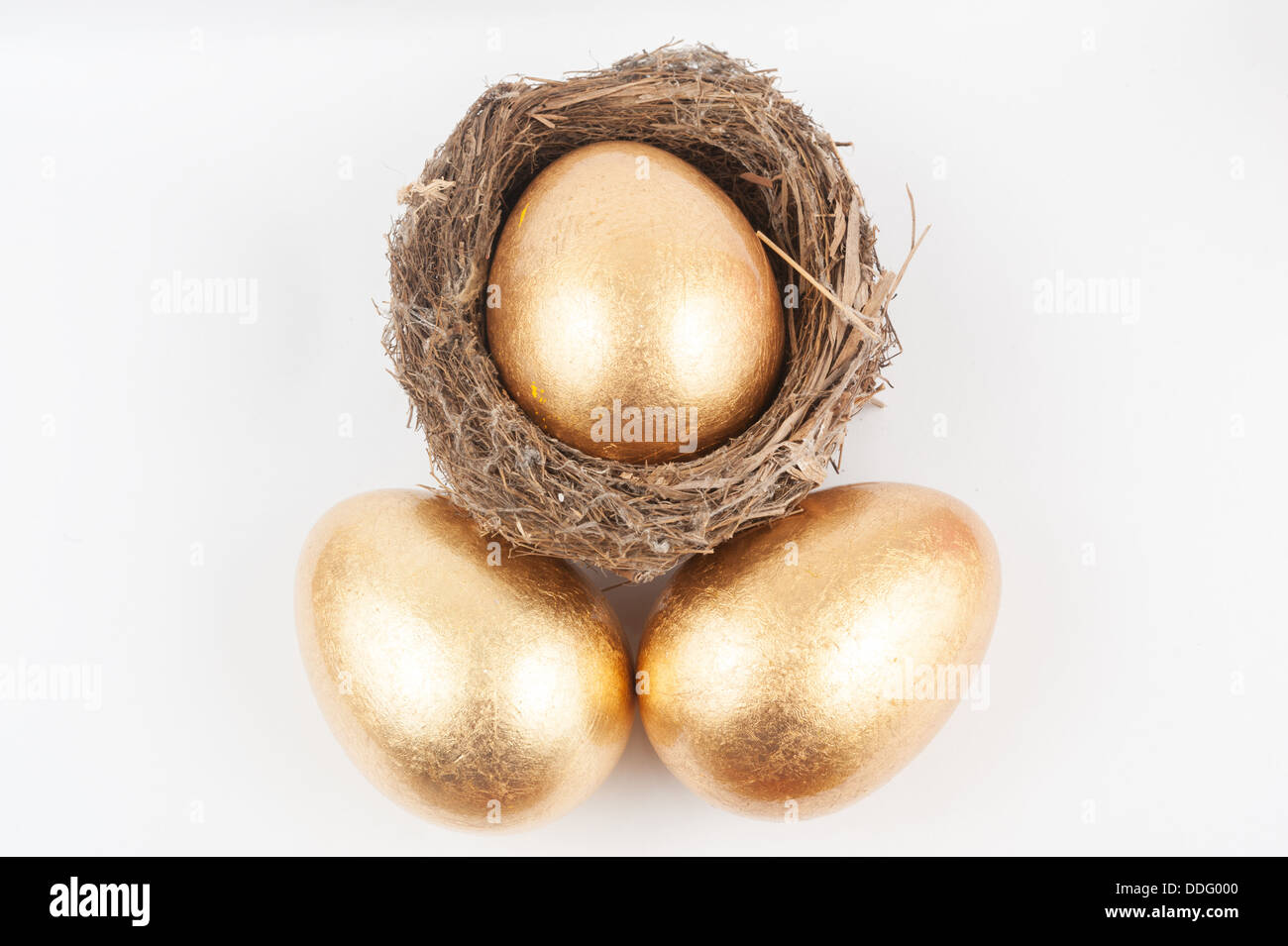 Un uovo dorato nel nido con due uova accanto ad esso Foto Stock