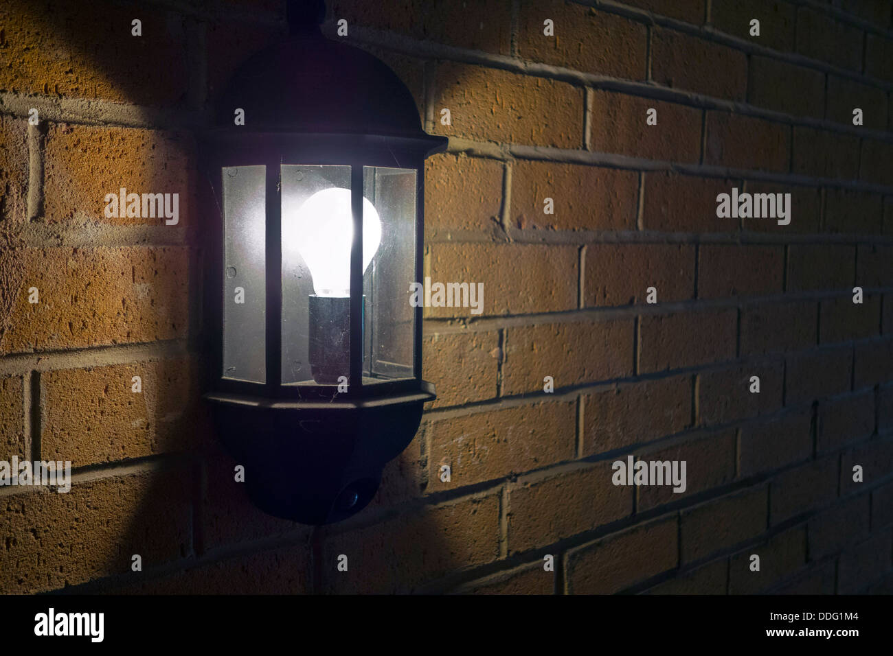 Luce elettrica su un muro di mattoni con ombre scure Foto Stock