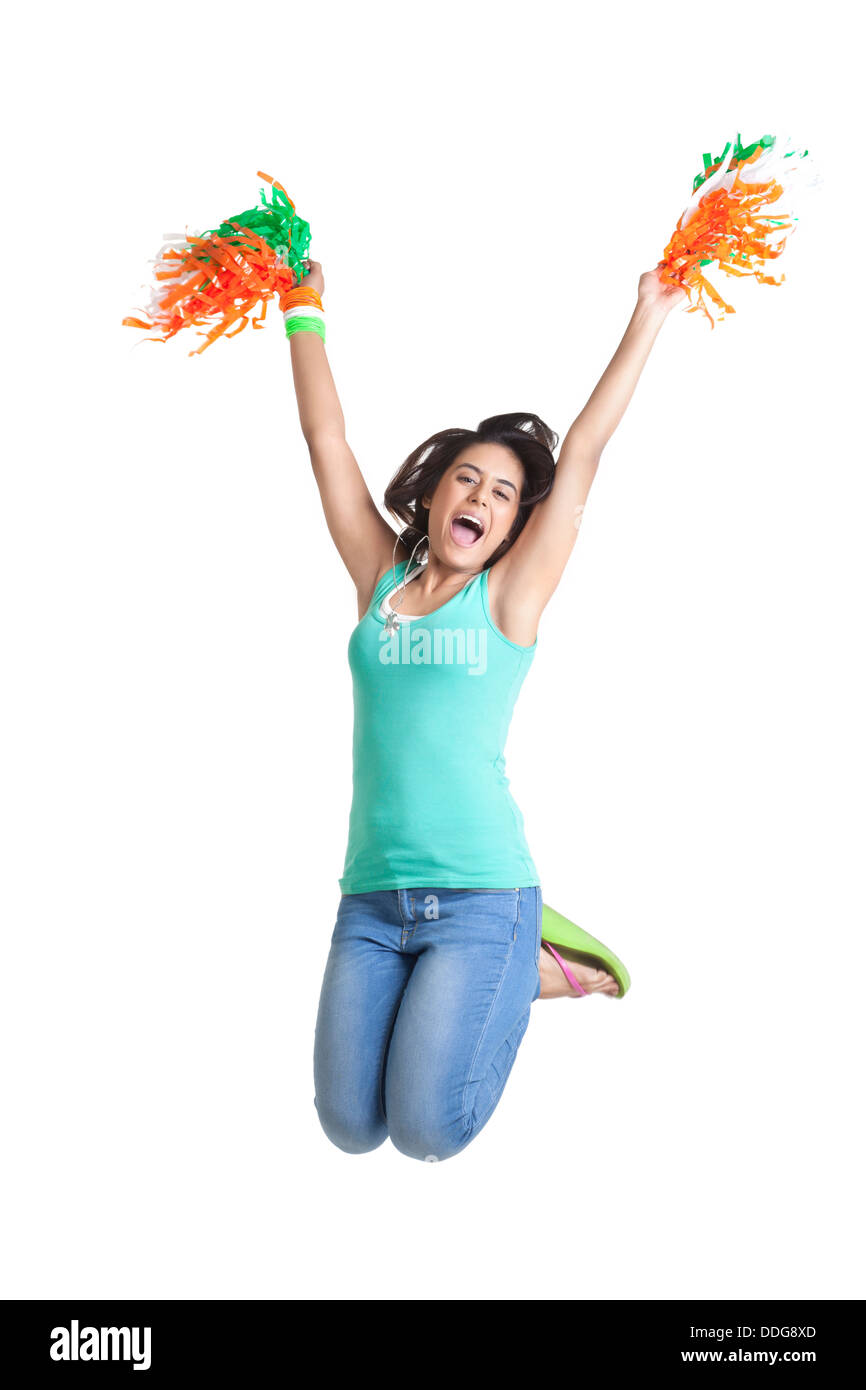 Excited donna giovane jumping in mid-air tenendo pom pom su sfondo bianco Foto Stock