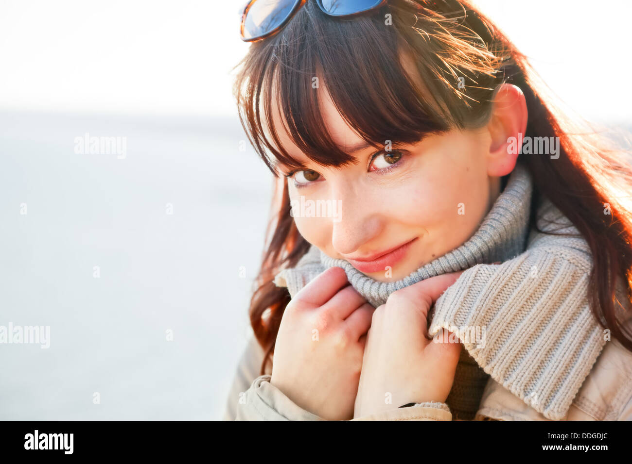 Ritratto di una giovane donna in piedi sul mare in una giornata di sole in inverno Foto Stock