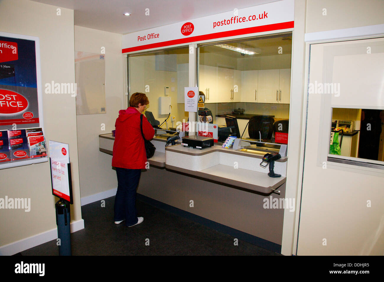 Woman in Red Jacket presso un ufficio postale contatore Foto Stock