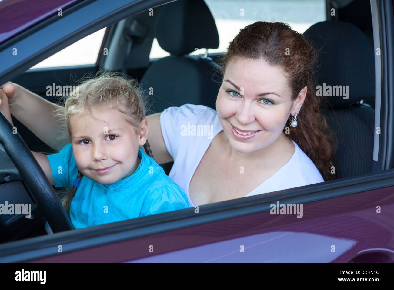 Felice madre caucasica con piccola figlia insieme seduta sul sedile di guida all'interno della vettura Foto Stock