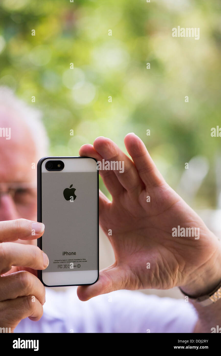Uomo senior di scattare una foto con un Apple iphone 5 Foto Stock