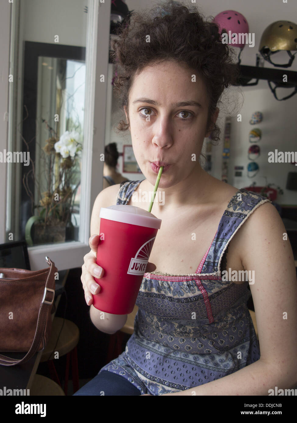 Giovane donna sorseggiando un frullato di frutta. Signor Foto Stock