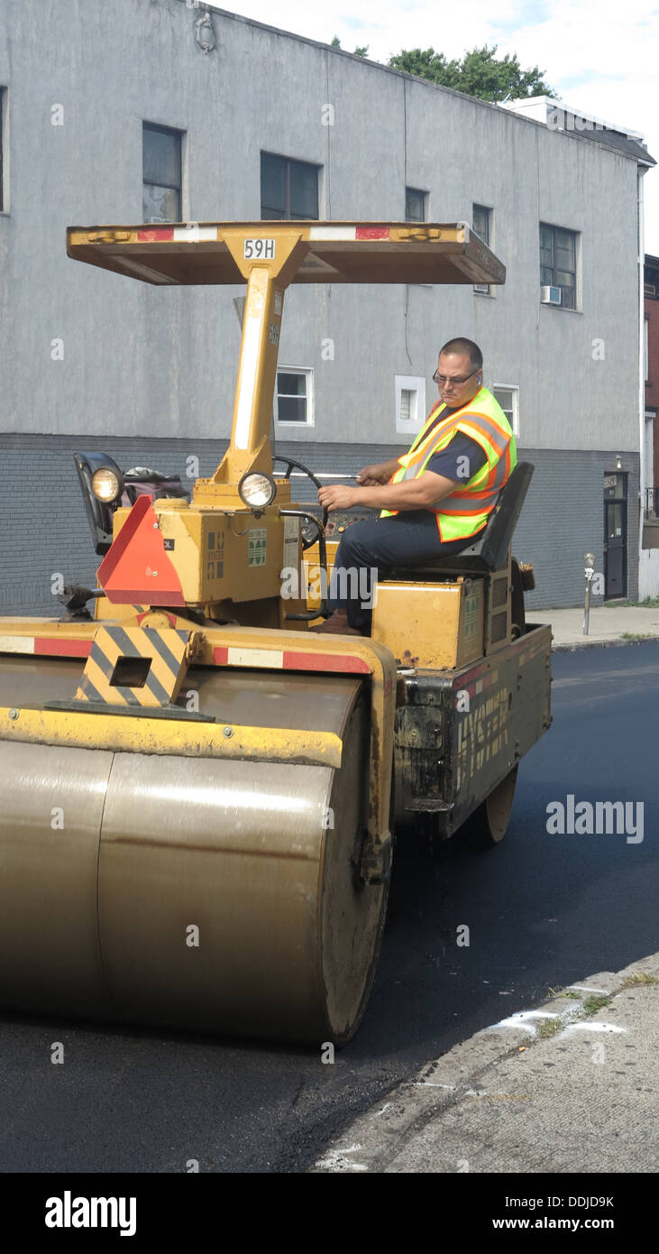Schiacciasassi regolarizza superficie su una nuova strada asfaltata a Brooklyn, New York. Foto Stock