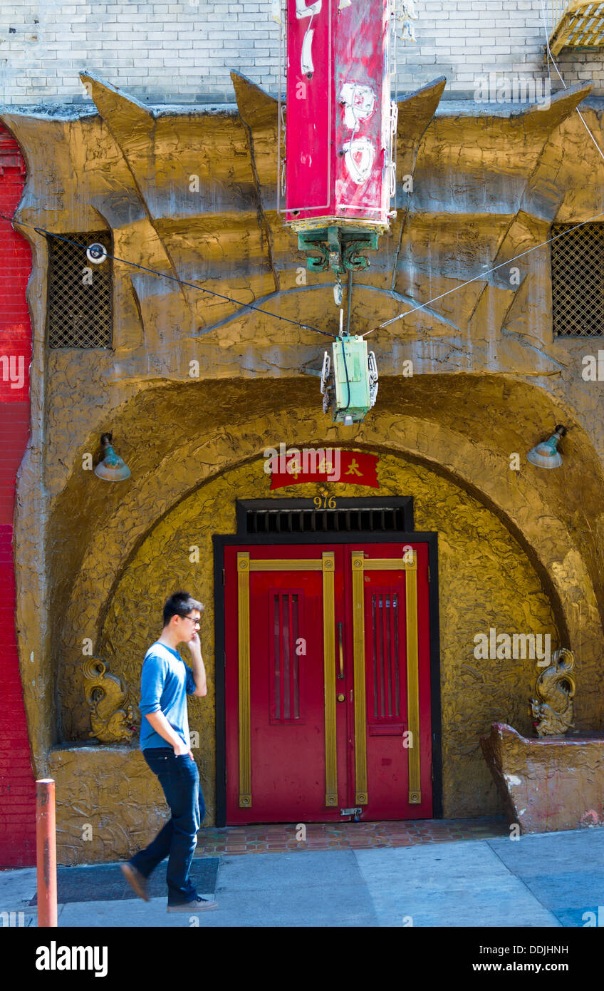 Giovane uomo su cellulare a piedi passato ornati in cinese tradizionale ingresso nella Chinatown di San Francisco che mostra la cultura il contrasto Foto Stock