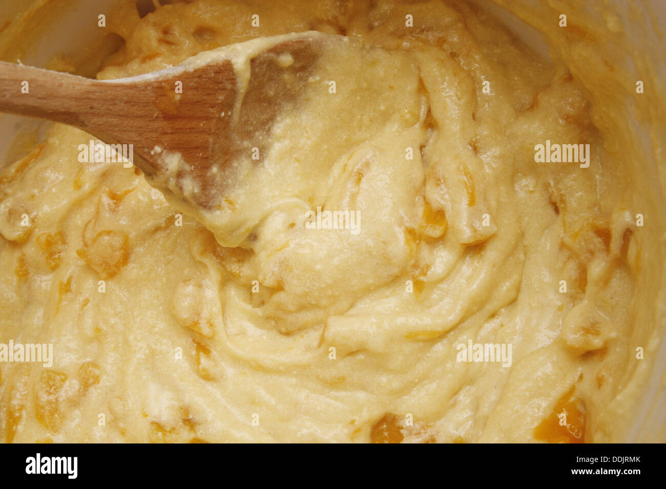Tortina di pesche pastella in bianco terrina con il cucchiaio di legno Foto Stock