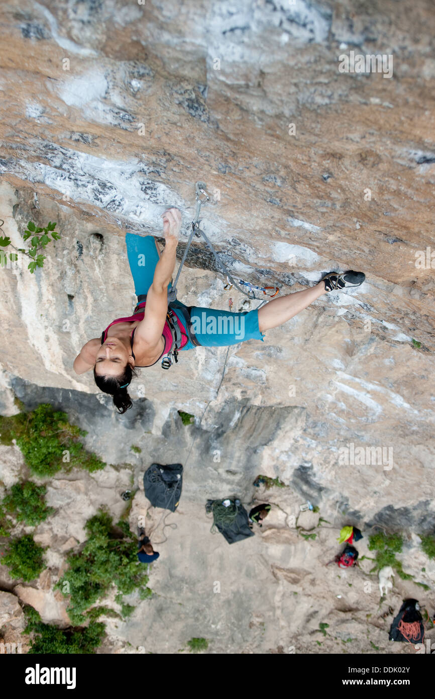 Vista in elevazione dello sport femminile scalatore. donna adulta che conduce a strapiombo di roccia calcarea. parete di arrampicata in massone. arco. L'Italia. Foto Stock