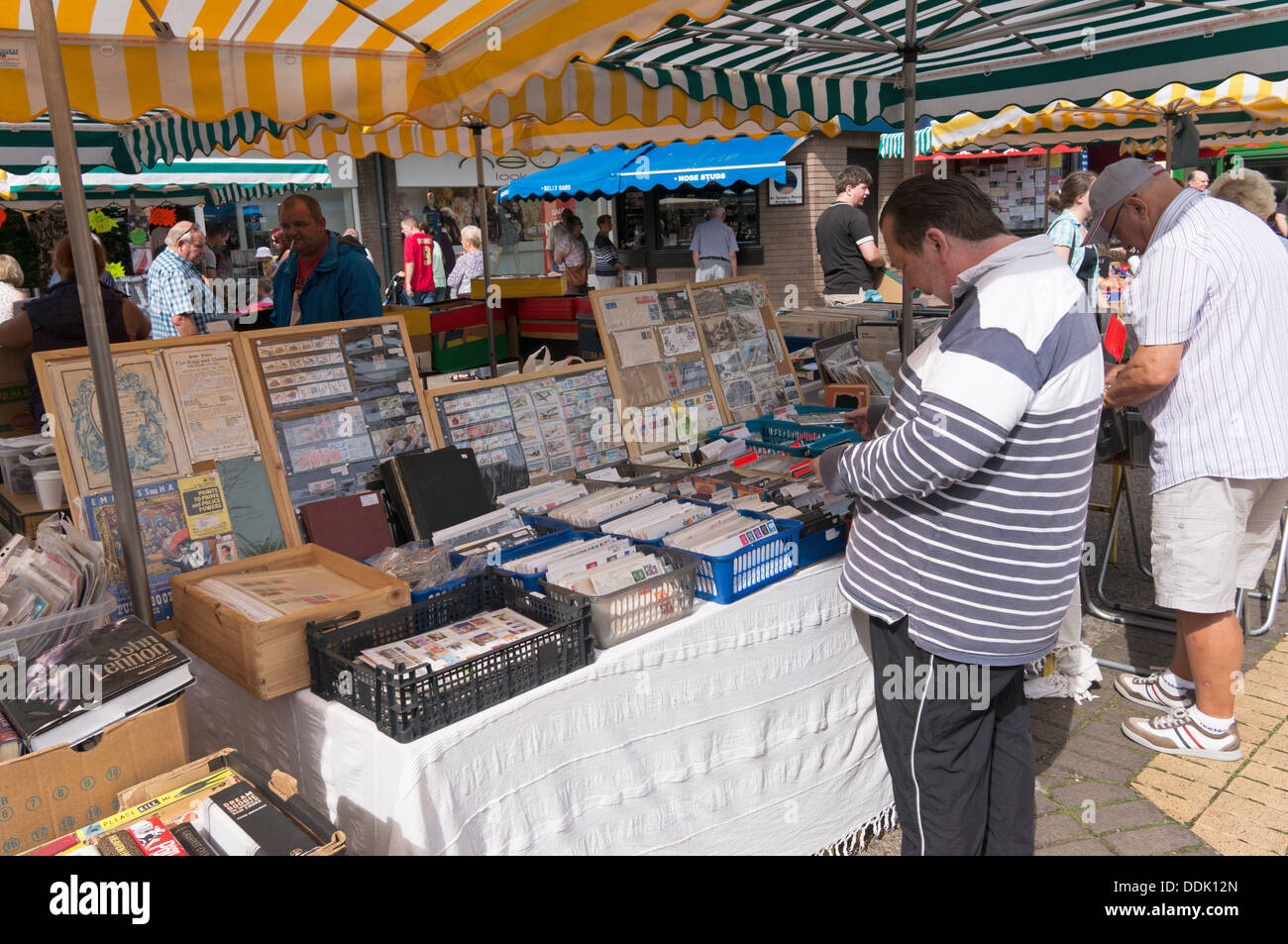 L'uomo navigando attraverso il francobollo collezione sul mercato in stallo Newton Abbot, England, Regno Unito Foto Stock