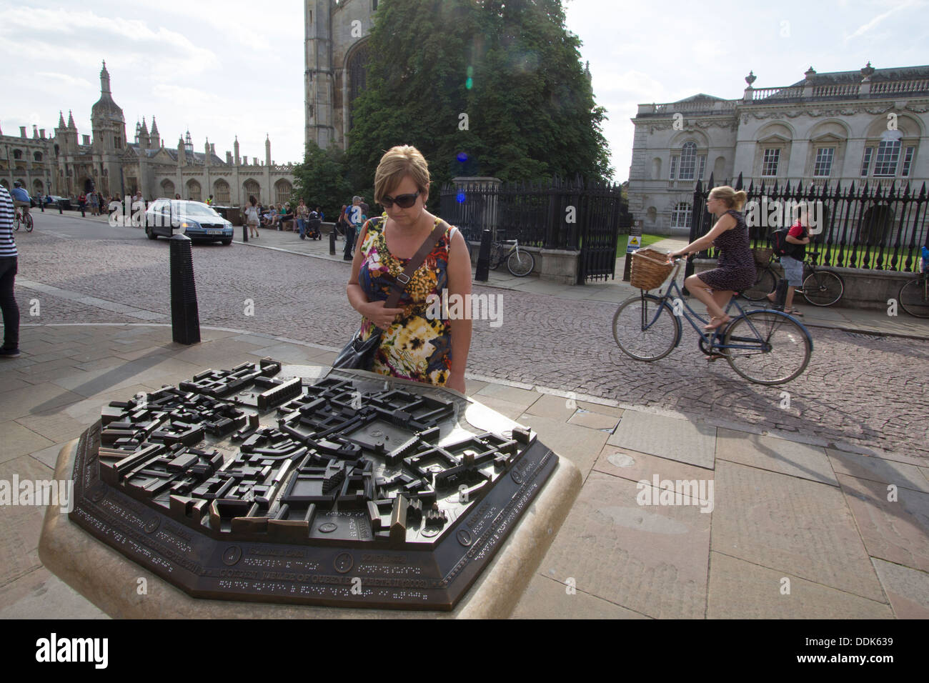 Una donna turistica studia la mappa in bronzo di Cambridge di fronte all'iconico King's College, Cambridge, Regno Unito. La mappa tattile fornisce una panoramica 3D del centro storico della città, guidando i visitatori attraverso il ricco patrimonio architettonico della città universitaria Foto Stock