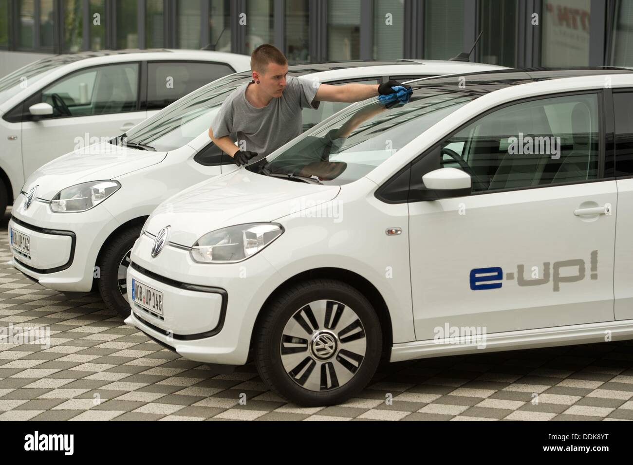 Wolfsburg, Germania. 04 Sep, 2013. L'uomo pulisce parabrezza di una Volkswagen e-up, Wolfsburg, Germania, 04 settembre 2013. Con l'e-up Volkswagen entra nel business del oure auto elettriche. Foto: Sebastian Kahnert/dpa/Alamy Live News Foto Stock