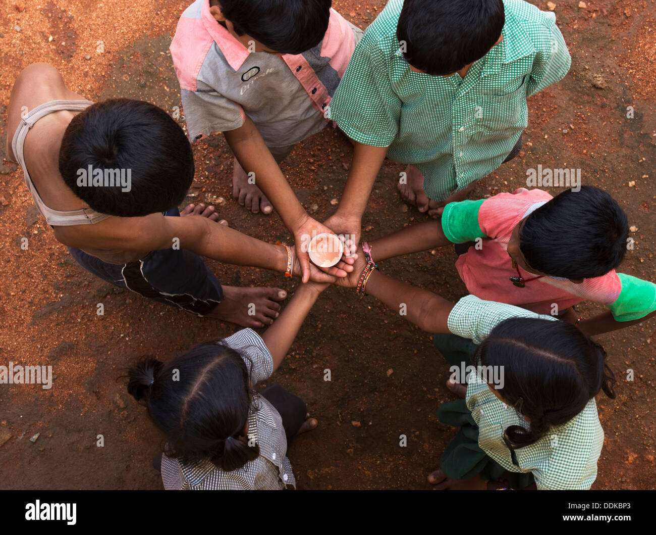 Rurale villaggio indiano mani per bambini in un cerchio tenendo in mano un cristallo globo di vetro / Massa / mondo. Andhra Pradesh, India Foto Stock