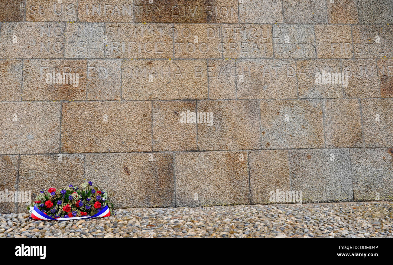 Corona di fiori alla base di un monumento di pietra per il 1 U.S. Divisione di fanteria presso la spiaggia di Omaha, in Normandia, Francia. Foto Stock