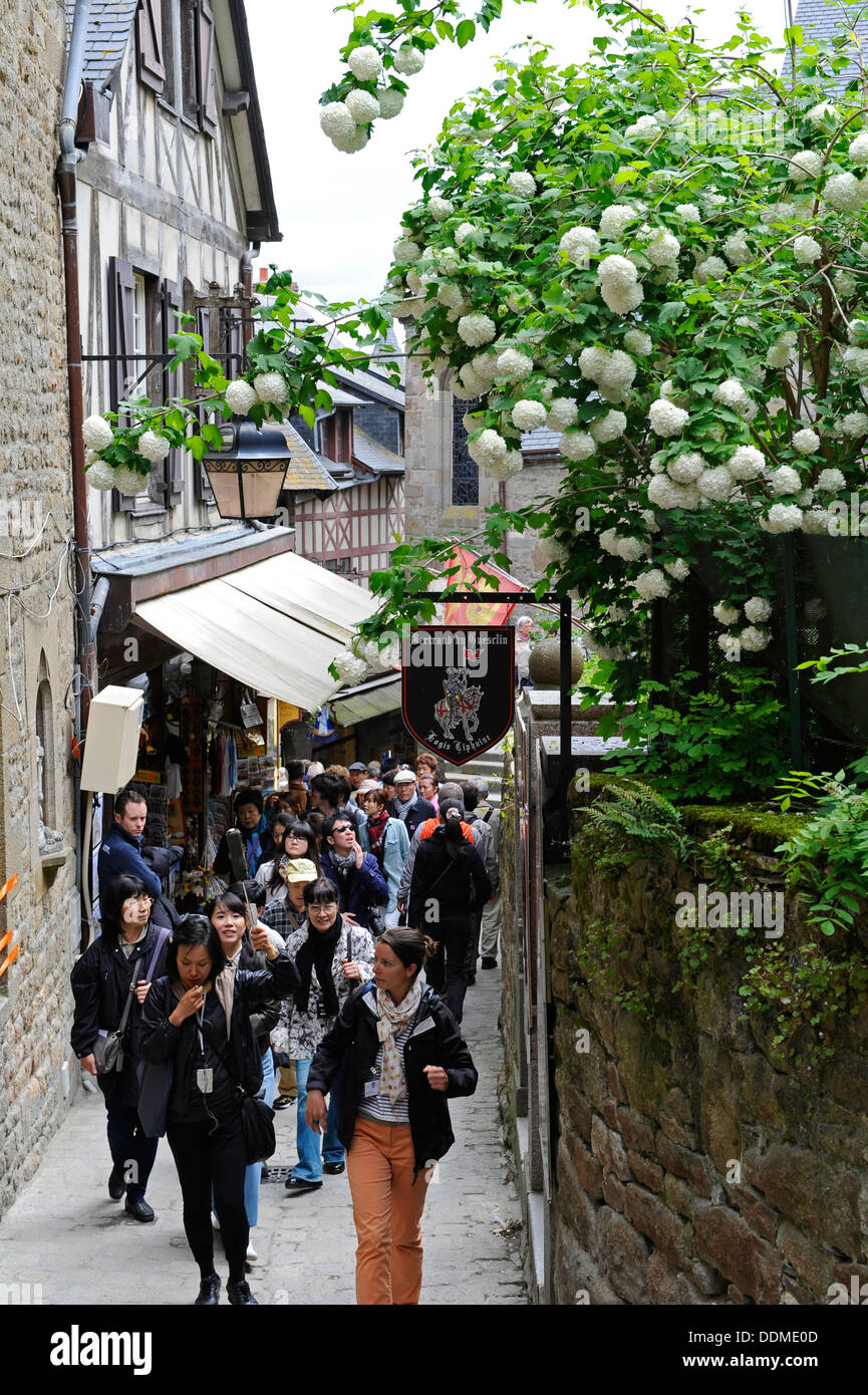 I turisti e gli amanti dello shopping a piedi attraverso le strette stradine che conducono alla abbazia di Mont Saint Michel, in Normandia, Francia. Foto Stock