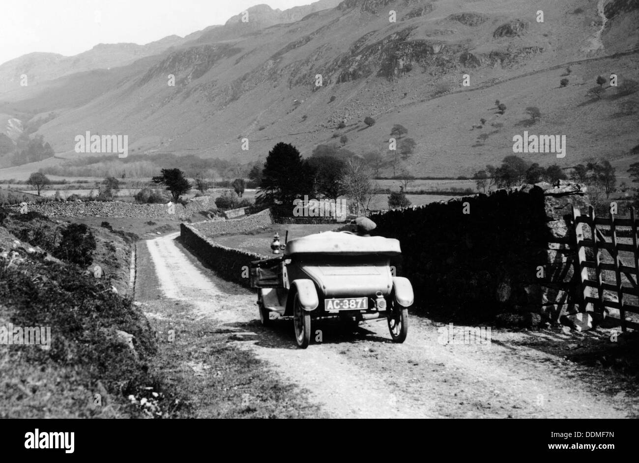 Un auto d'epoca che viaggiano lungo una corsia attraverso il Lake District, Cumbria, 1920s. Artista: sconosciuto Foto Stock