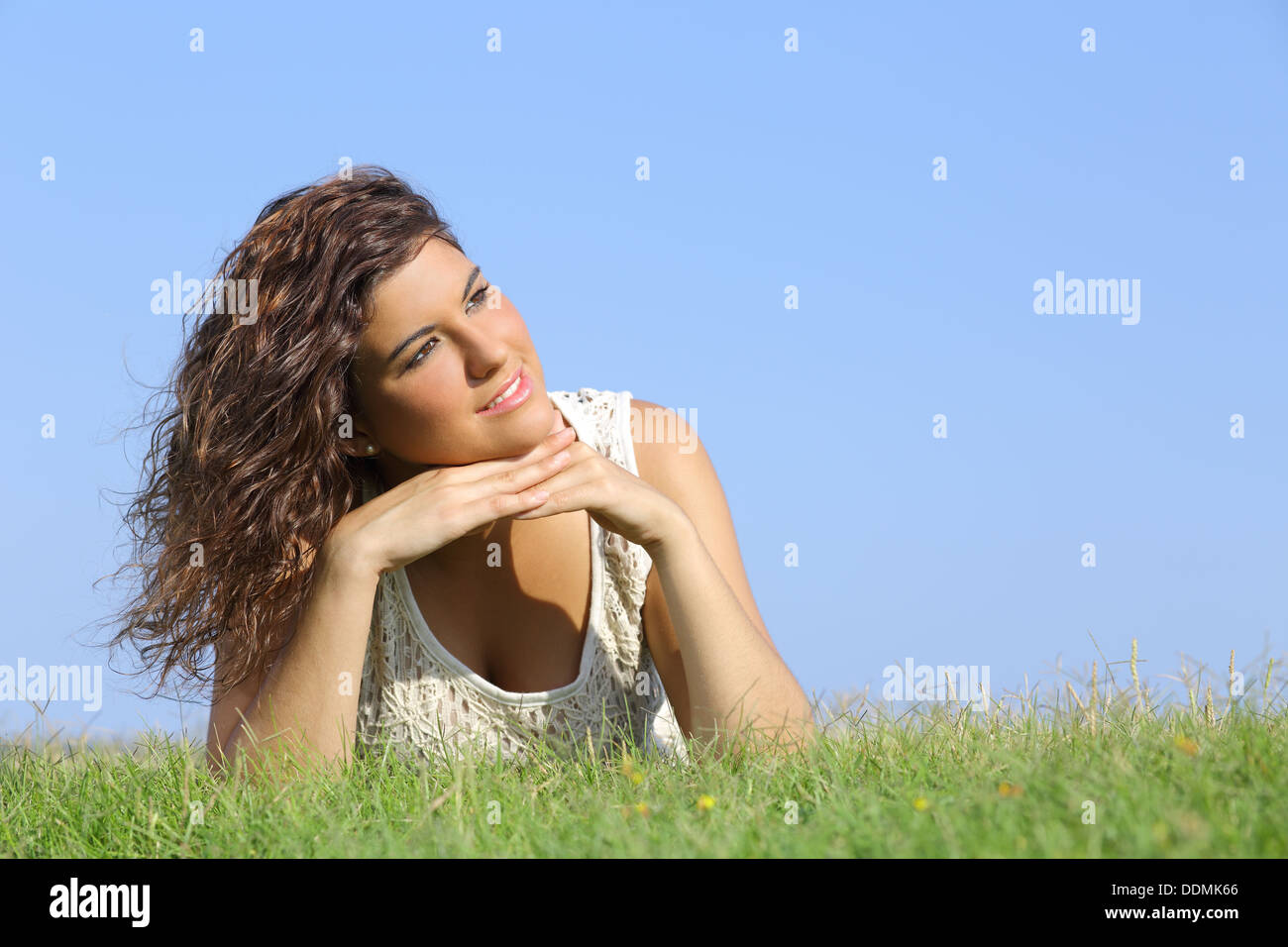 Ritratto di una donna bellissima sdraiati sull'erba con un cielo blu in background Foto Stock