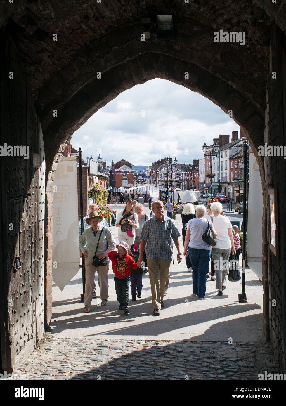 I turisti a piedi attraverso la porta ad arco nelle mura della città di Ludlow, England, Regno Unito Foto Stock