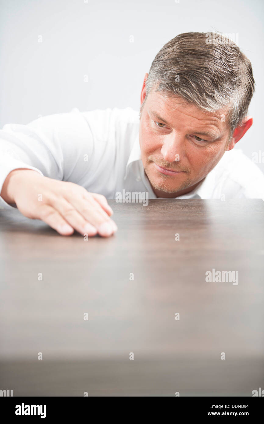 L'uomo il controllo della superficie di un tavolo di legno Foto Stock