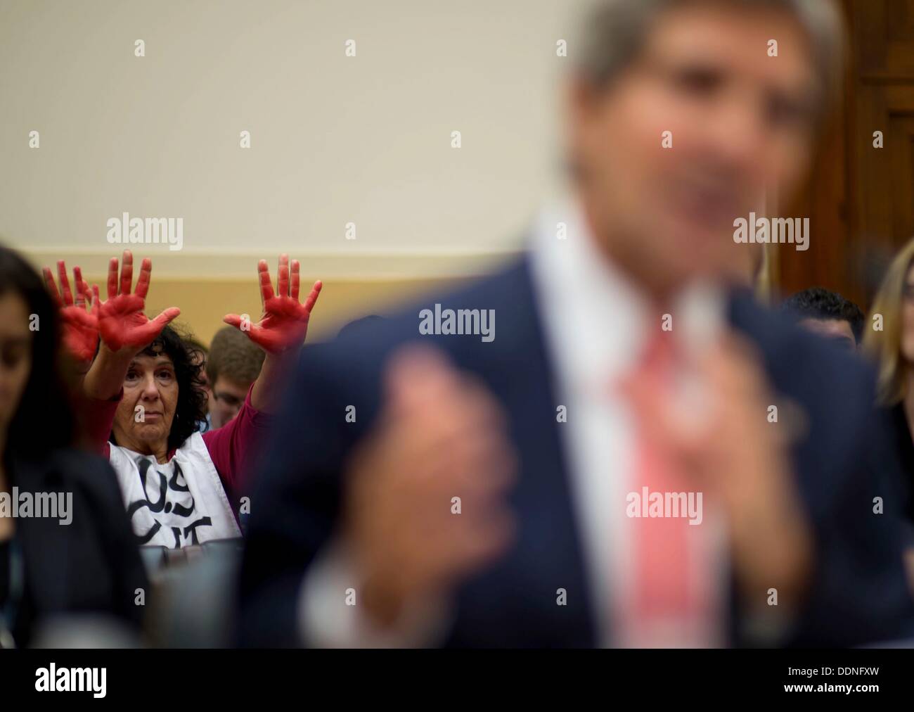 Un manifestante con codice colore rosa alza le mani colorate con inchiostro rosso nel corso di una audizione sulla Siria prima casa Commissione Affari Esteri il 4 settembre 2013 a Washington DC. Durante l' audizione, Kerry, Hagel e presidente del Joint Chiefs gen. Martin Dempsey discusso i possibili interventi militari in risposta all'uso di armi chimiche da parte della Siria sul loro stesso popolo. Foto Stock