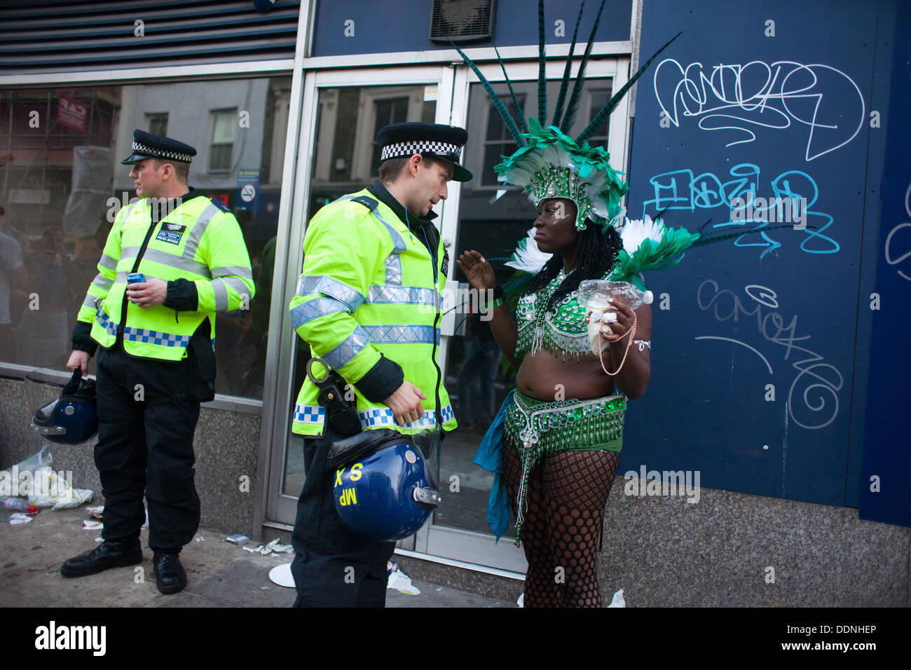 Una femmina nero carnevale attore vestito in verde parla di un bianco funzionario di polizia in tenuta da sommossa in Portobello Road. Foto Stock