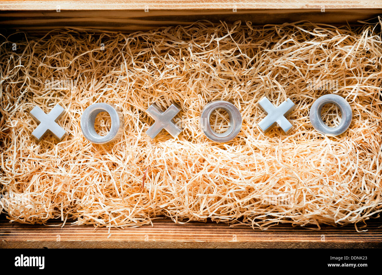 Baci e abbracci xoxo simboli in un regalo in legno scatola riempita con rafia naturale Foto Stock