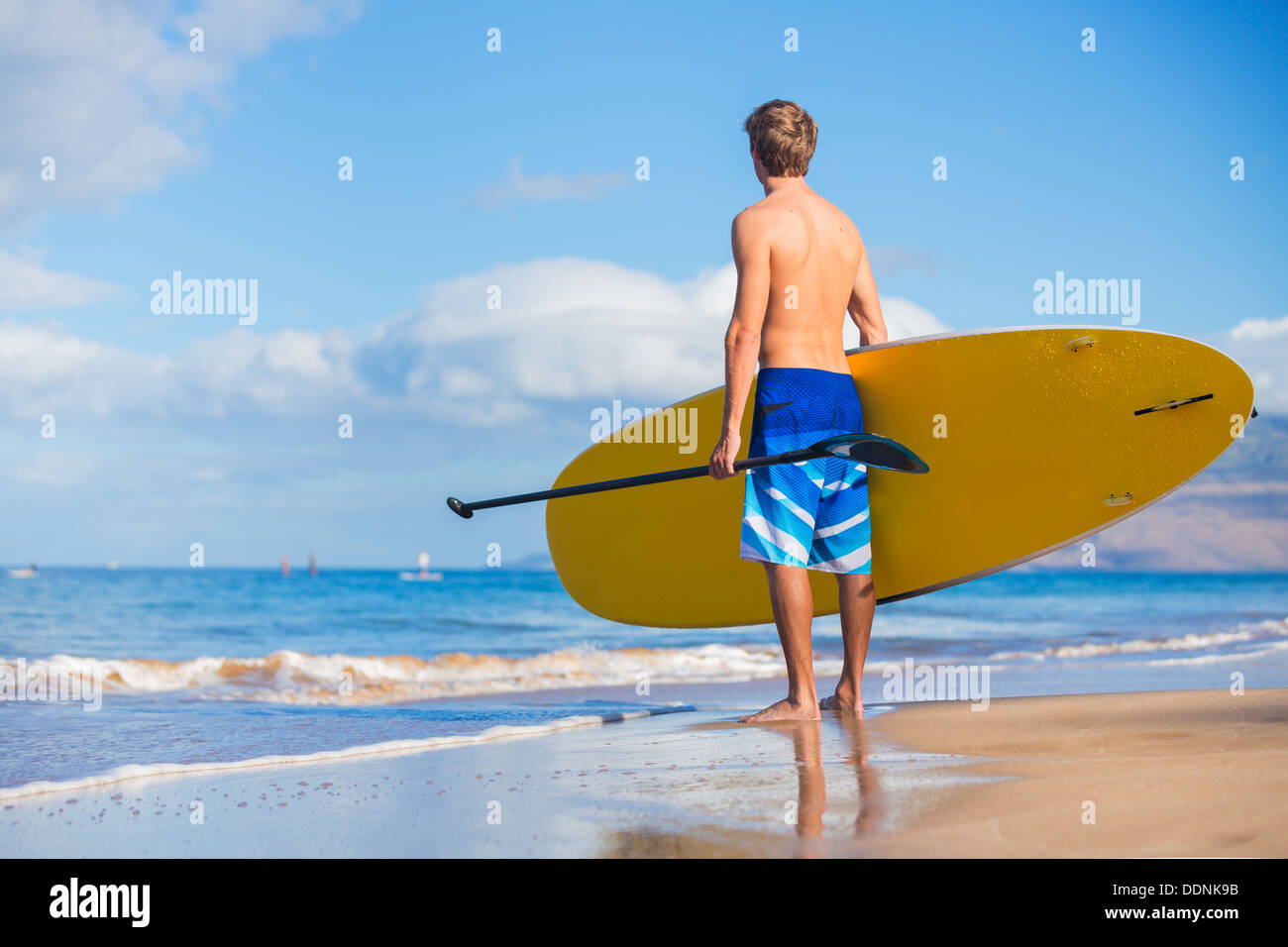 Uomo con Stand Up Paddle Board, SUP, sulla spiaggia alle Hawaii Foto Stock