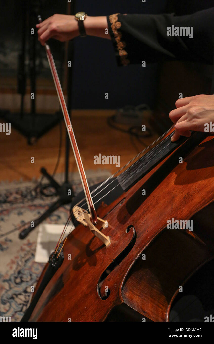Close up violoncellista con le mani in mano e la prua mentre suona un violoncello Foto Stock