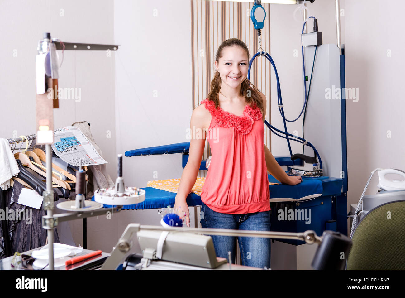 Una giovane donna degno nella stanza di lavoro al servizio stireria Foto Stock