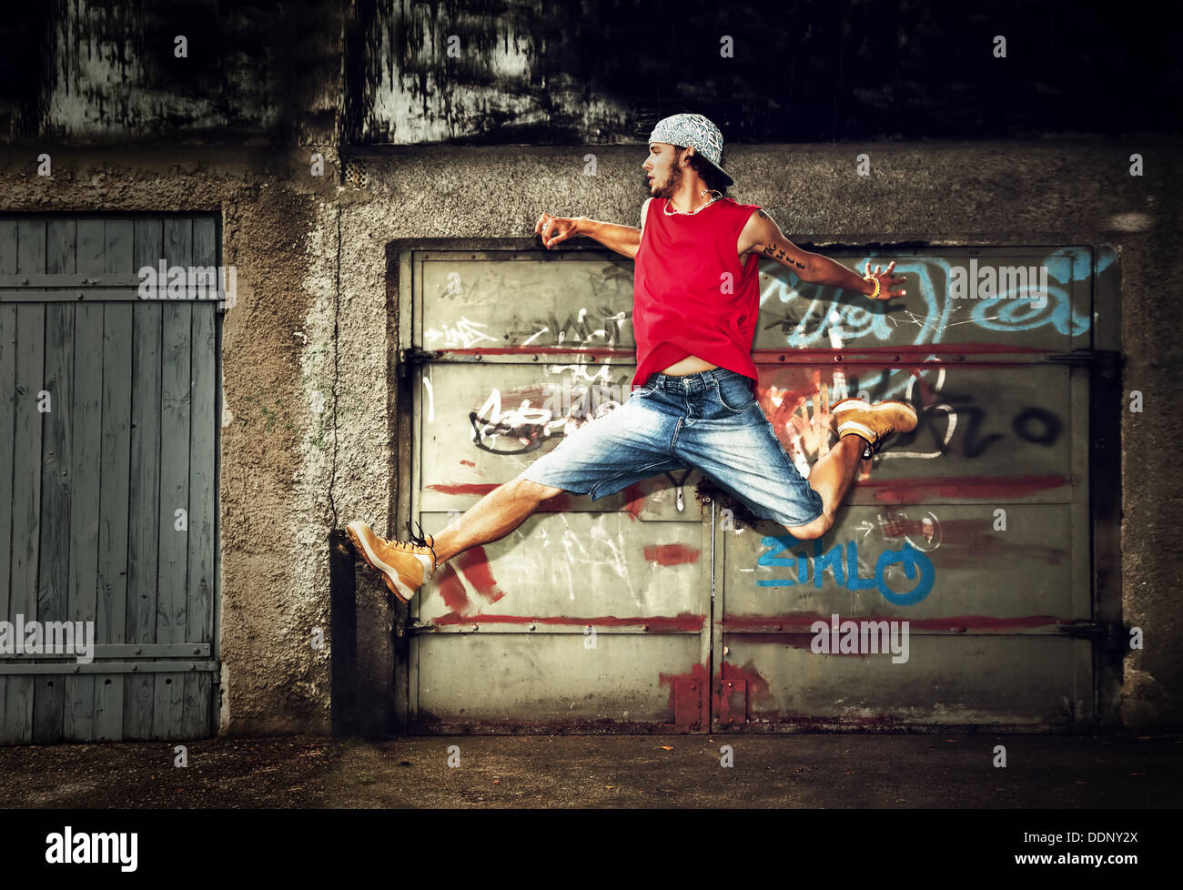 Giovane uomo / teen jumping / dancing su grunge graffiti sullo sfondo della parete Foto Stock