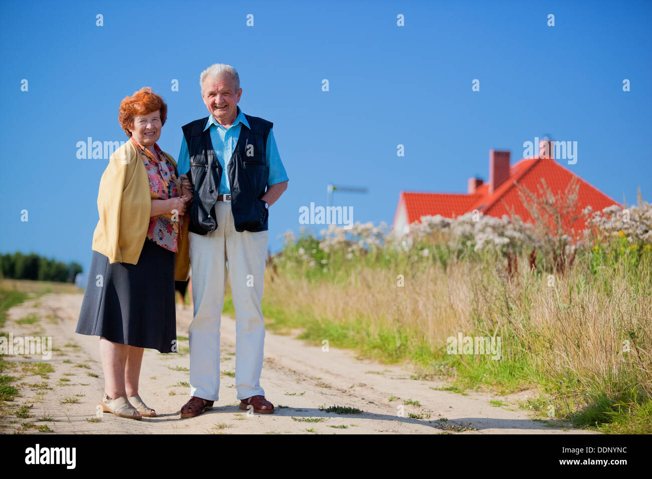 Felice coppia senior davanti alla loro casa Foto Stock