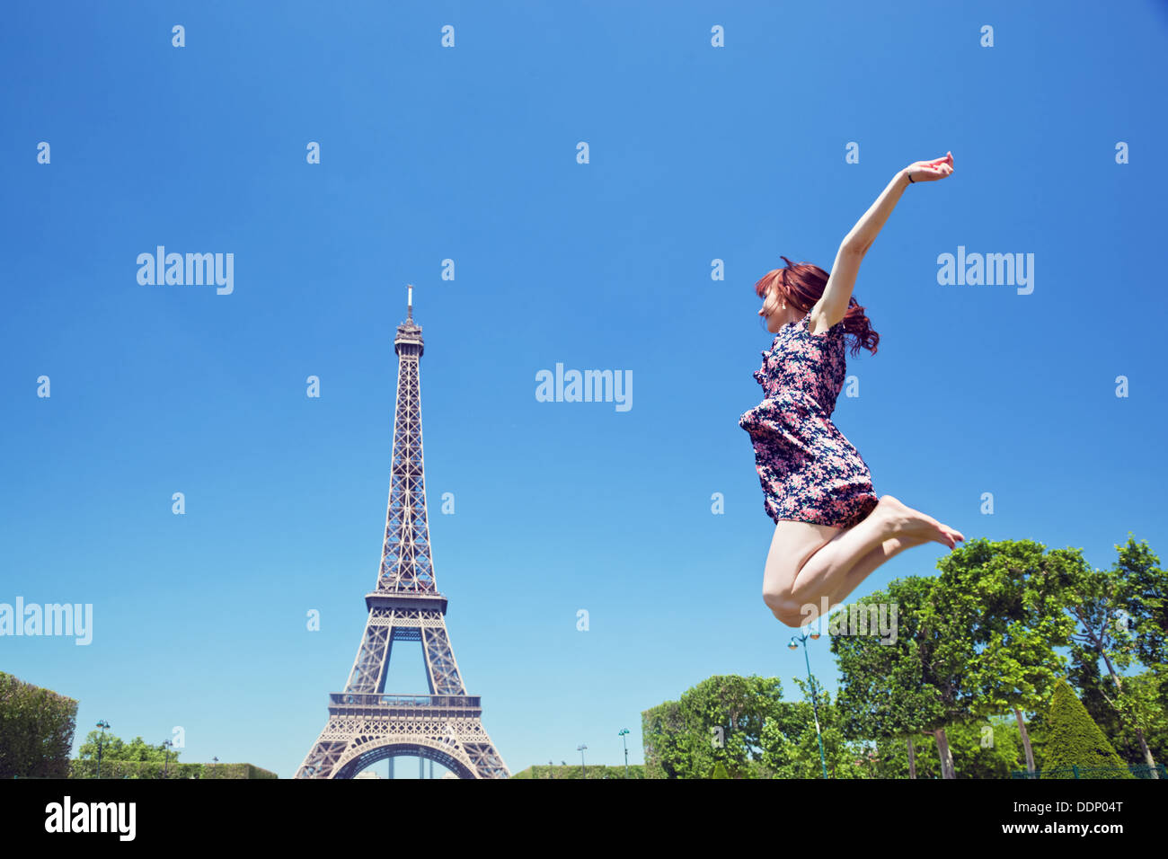 Giovane donna felice salti di gioia contro la Torre Eiffel a Parigi, Francia Foto Stock
