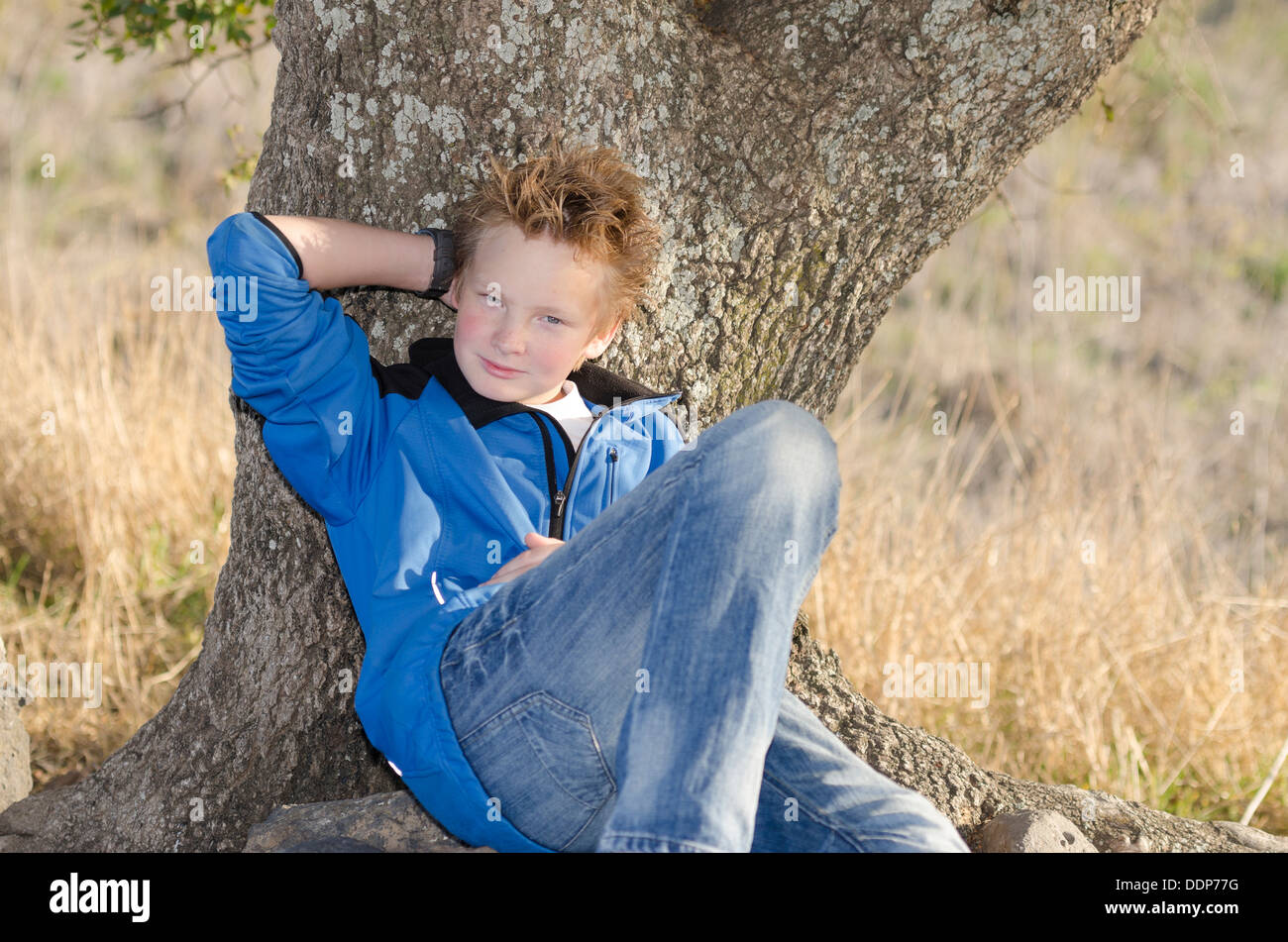 Adolescente in sportswears siede sotto agli alberi in natura Foto Stock