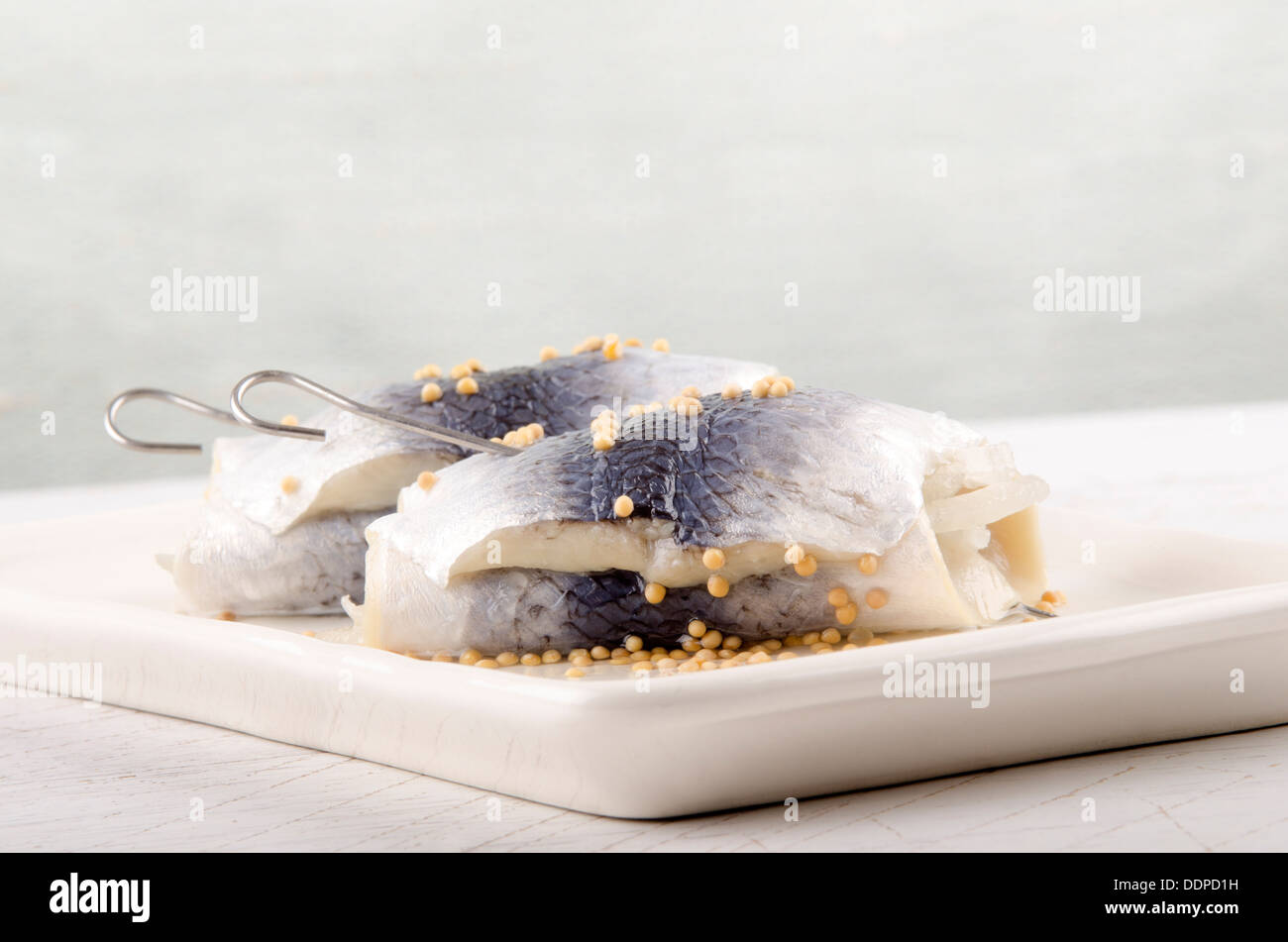 Aringhe in salamoia con seme di senape su una piastra Foto Stock