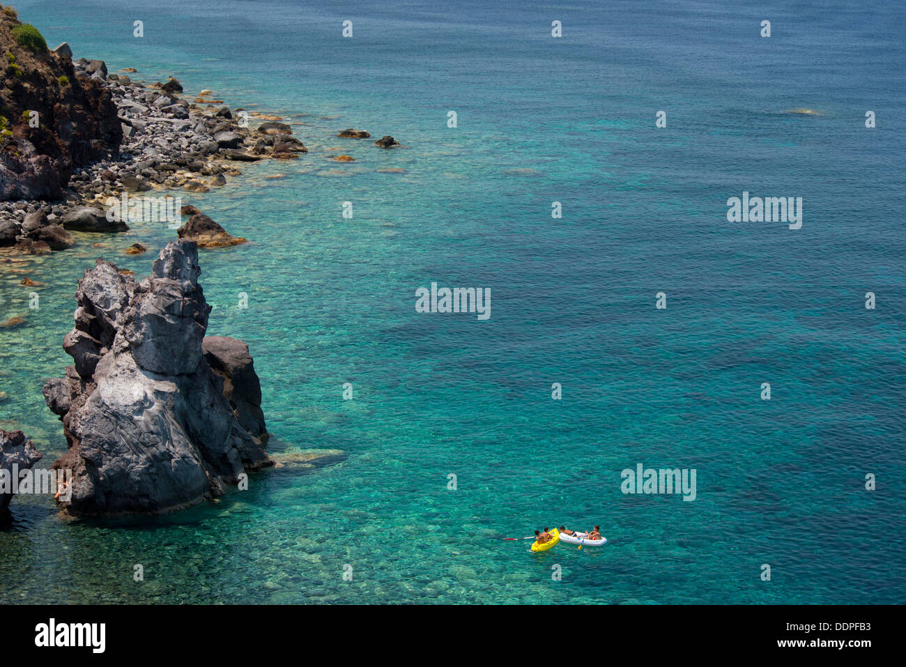 Persone su zattere in una caletta rocciosa vicino a Malfa nell'isola di Salina, le Isole Eolie, Messina, Sicilia, Italia Foto Stock