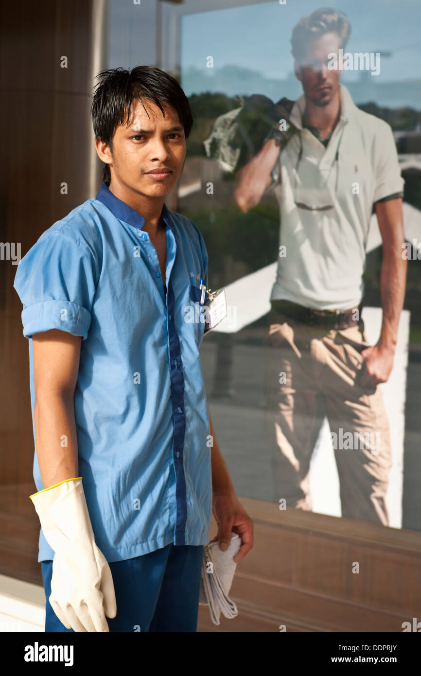 Giovane uomo asiatico pulizia negozio finestra, KL Foto Stock